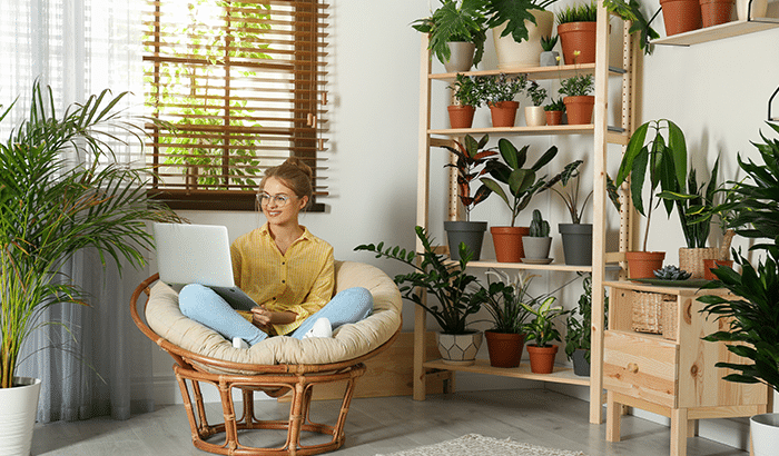 A beautify lady sitting on cushion and watch video on a laptop and smiling.